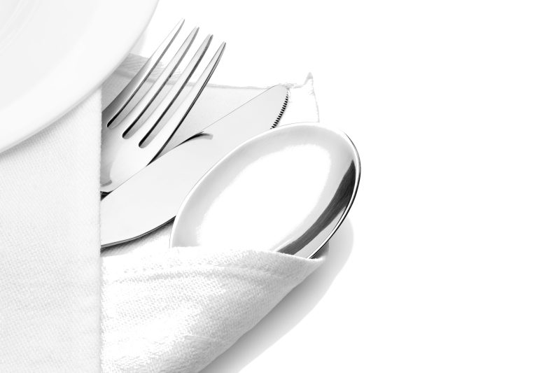Cuchillo, tenedor y cuchara envueltos en servilleta de lino en fondo blanco