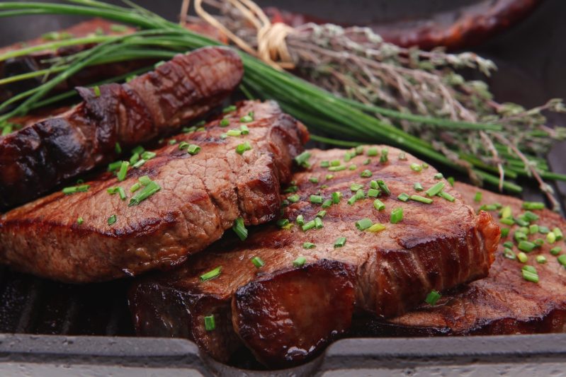 carne fresca de ternera asada madura en una sartén a la parrilla con tomillo y pimienta aislada en fondo blanco